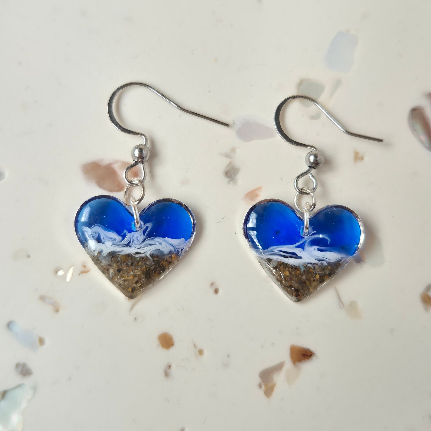 close up of heart welsh beach sand earrings against a natural background