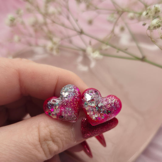Sparkling red and pink heart earrings with glitter highlights.