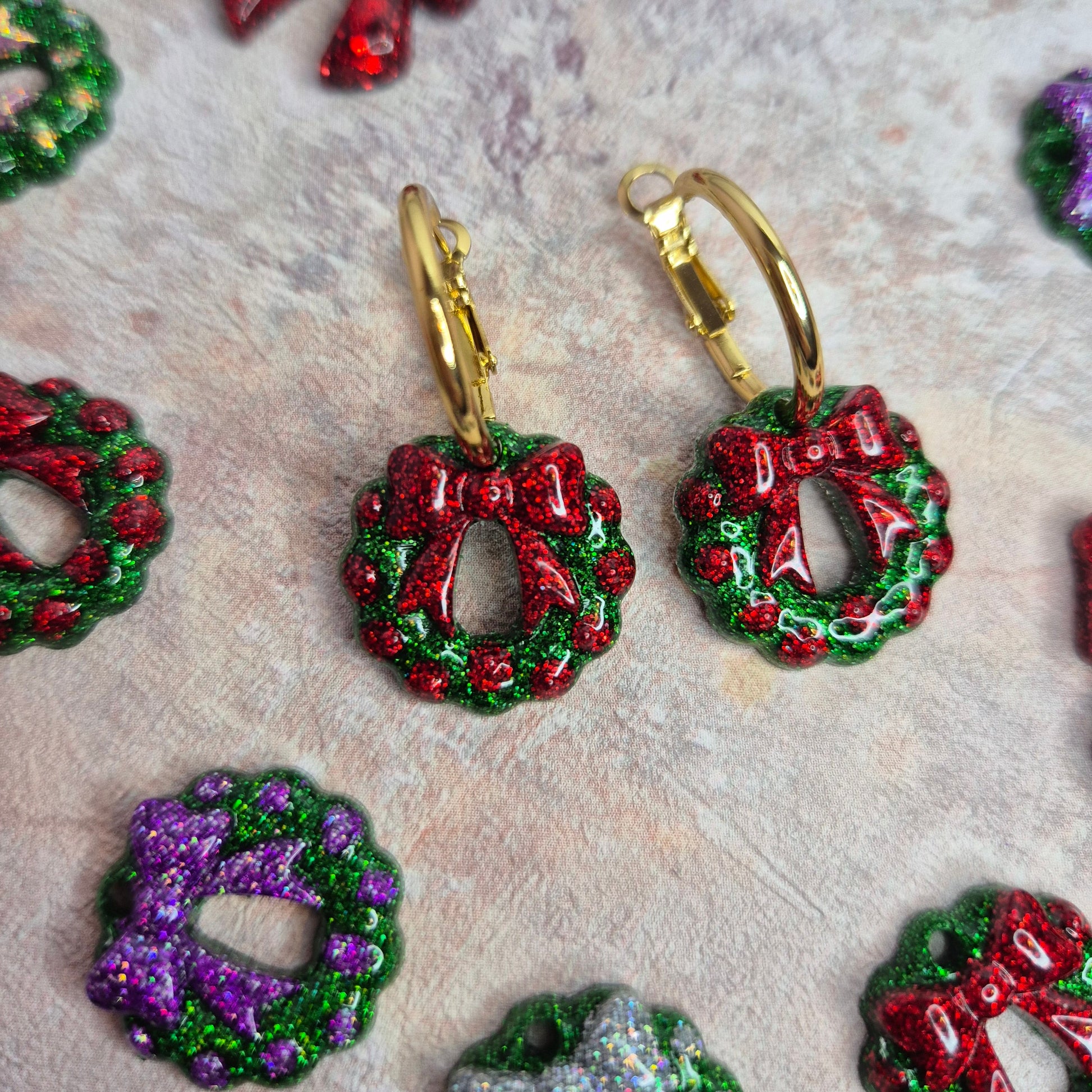 Colorful wreath-shaped earrings on a textured surface