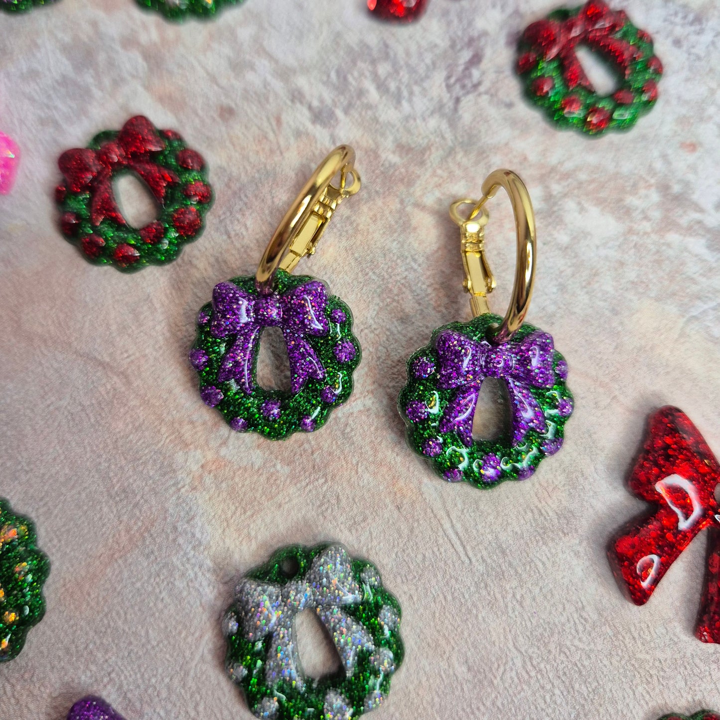 Colorful decorative wreath-shaped earrings on a textured surface