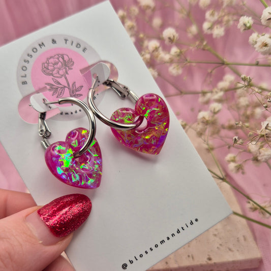 Handmade resin heart earrings with shimmering pink dichroic film.
