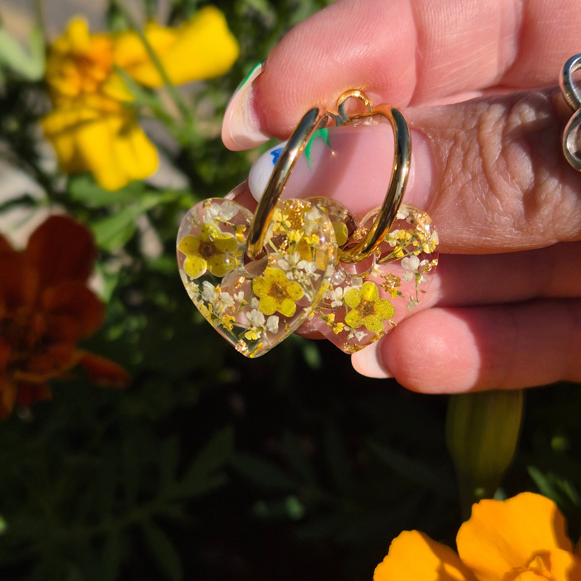 heart shaped resin earrings with real flowers and wood pulp flowers on gold hoops