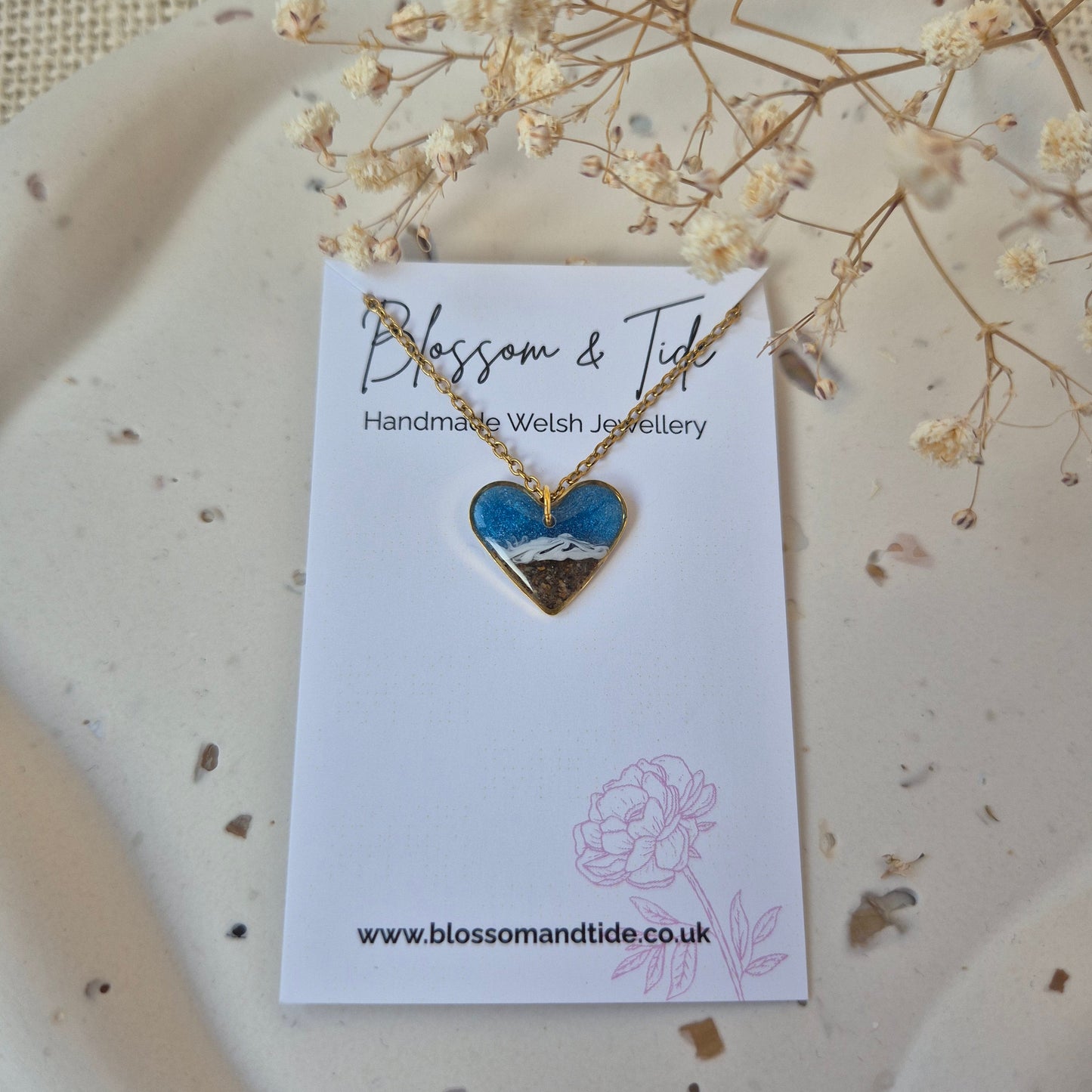 Heart-shaped necklace on a branded card with dried flowers