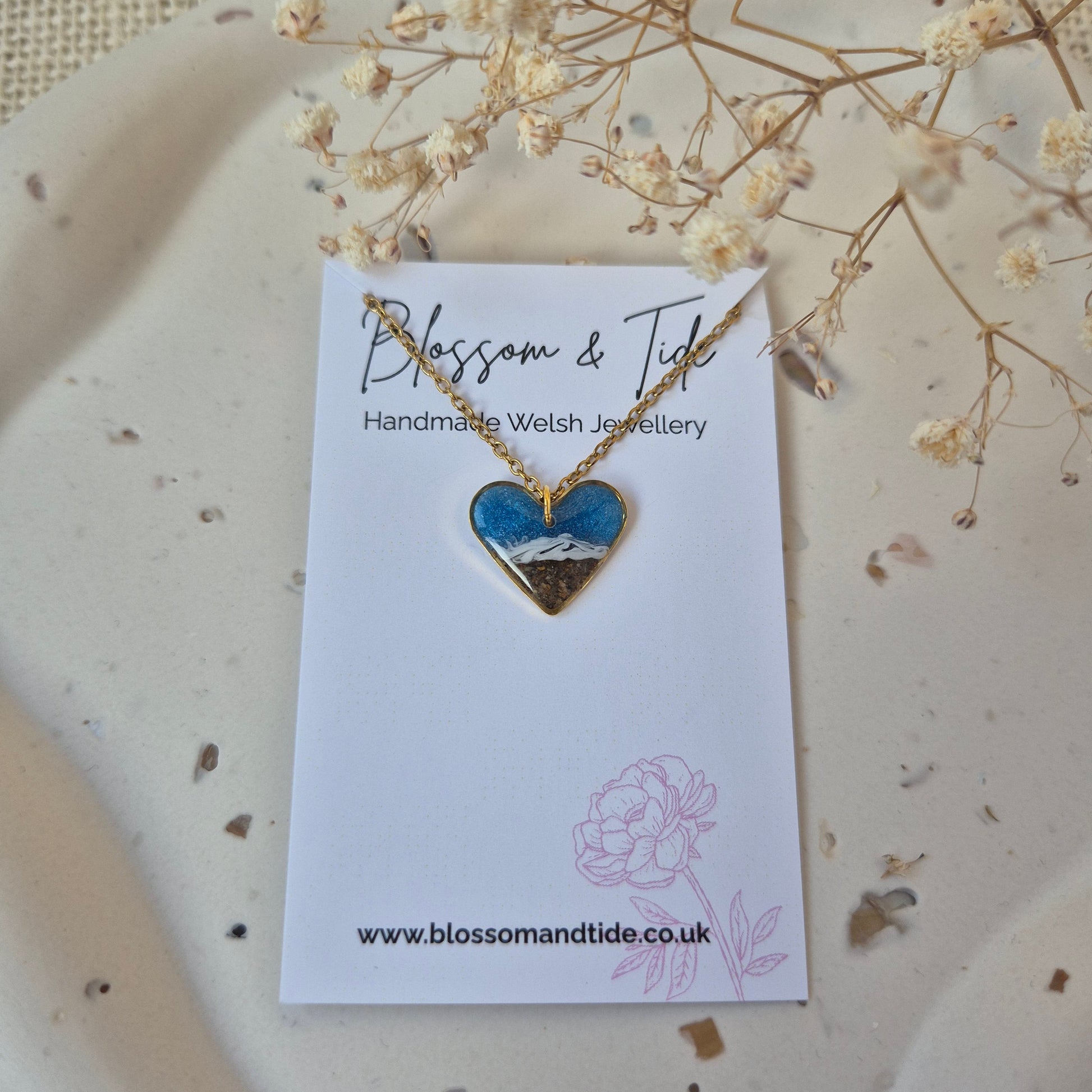 Heart-shaped necklace on a branded card with dried flowers