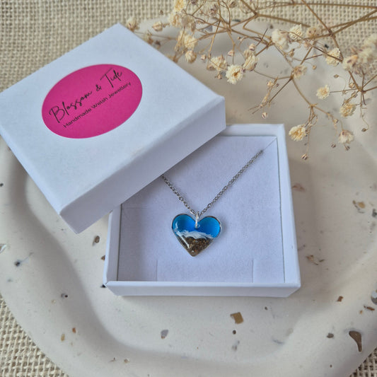 Necklace with a heart-shaped pendant in a white box on a textured surface