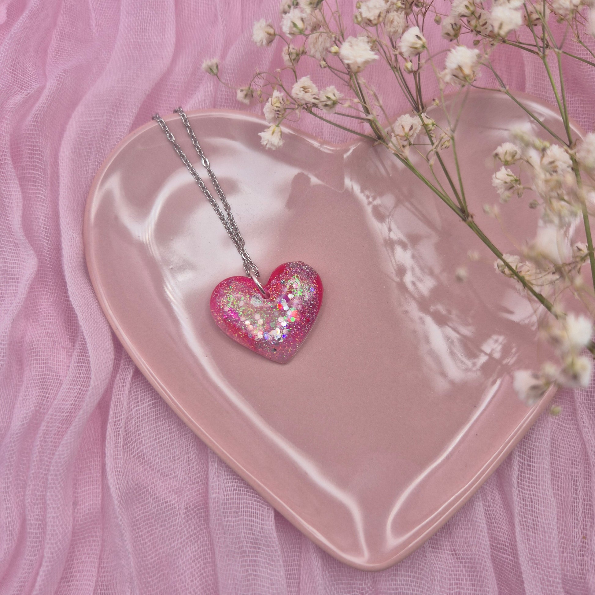 Heart-shaped resin necklace with red, pink, and glitter accents.