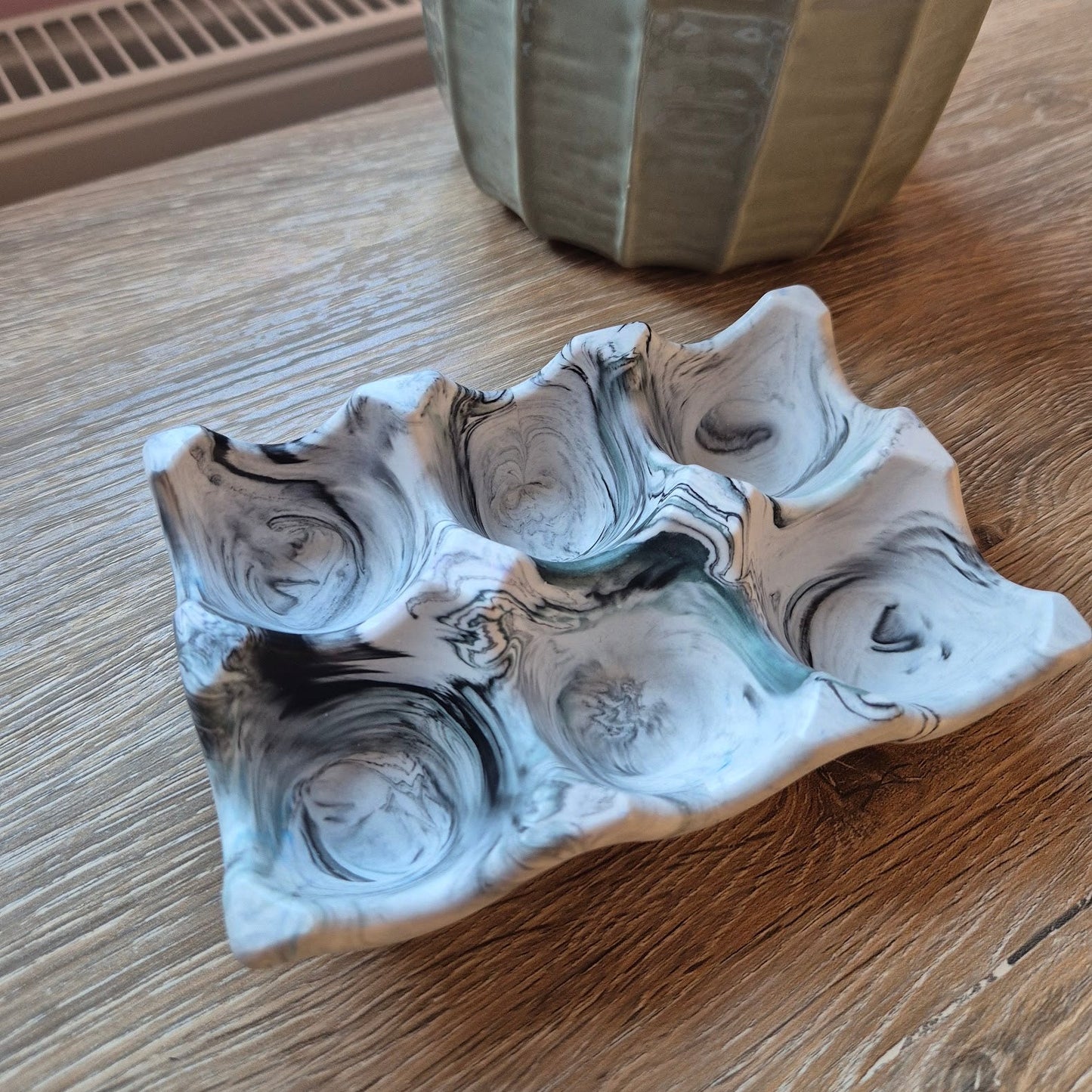 Black marble egg tray on a wood table with a plant in the background