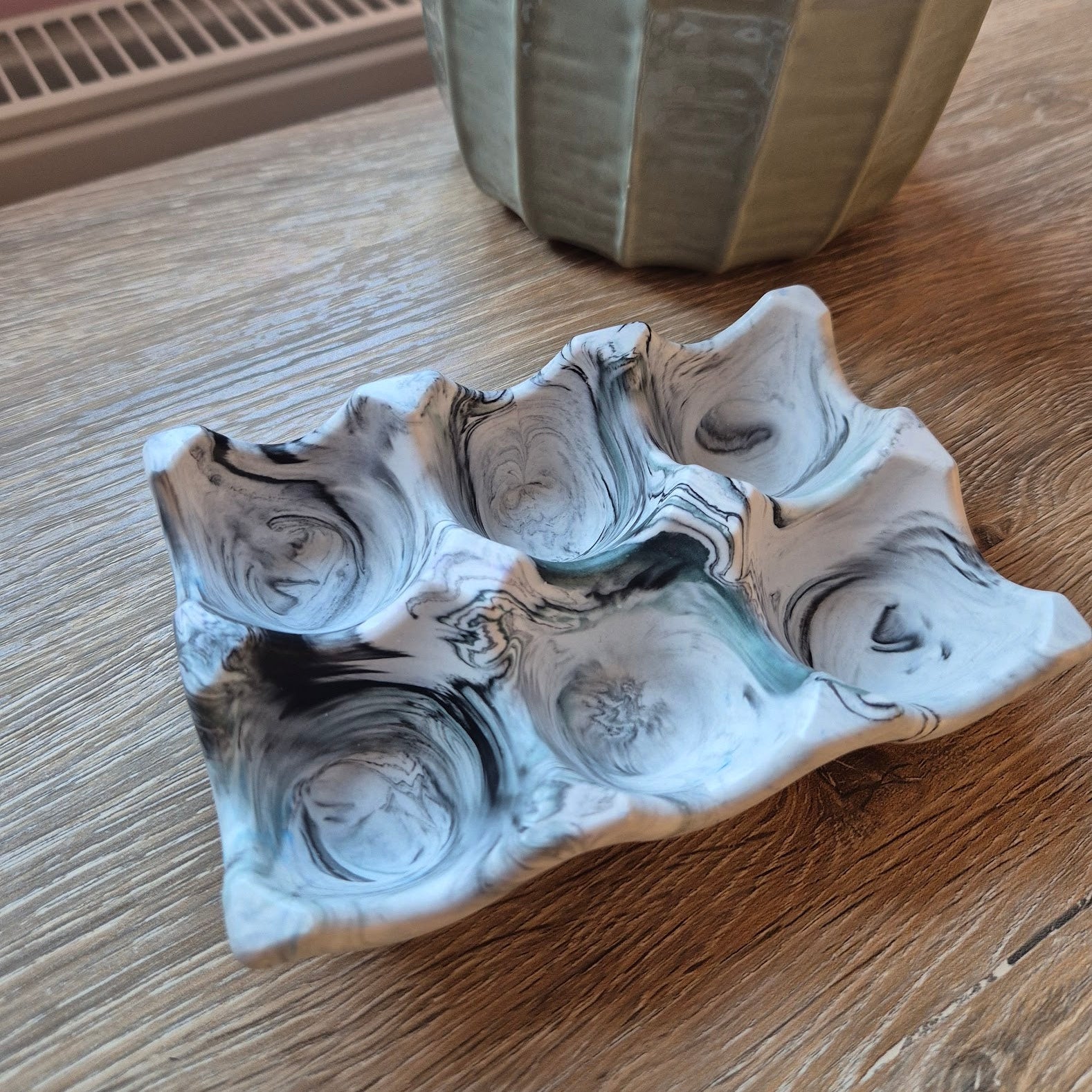 Black marble egg tray on a wood table with a plant in the background