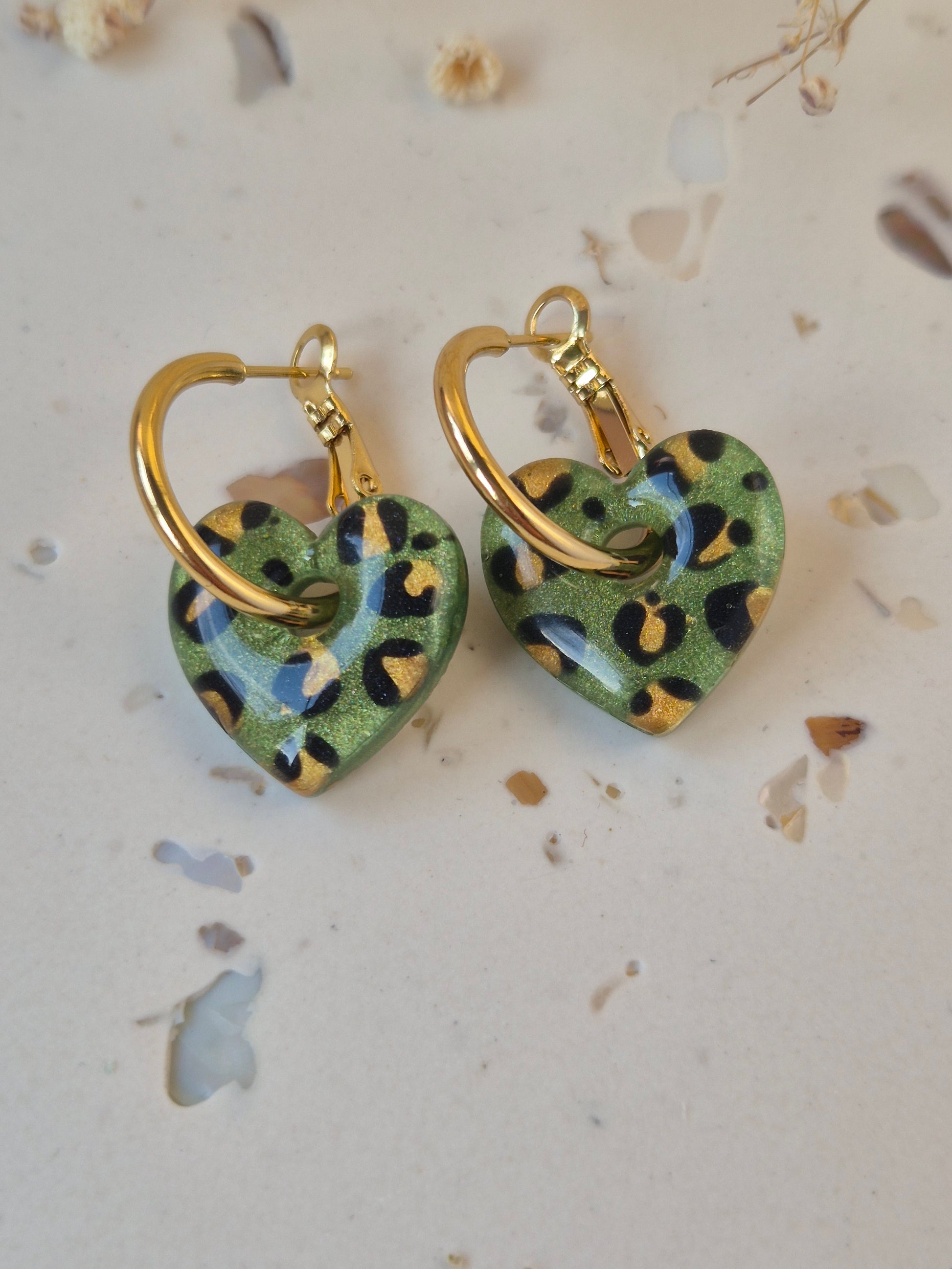 close up of Olive green leopard print heart earrings on gold hoop against a neutral background