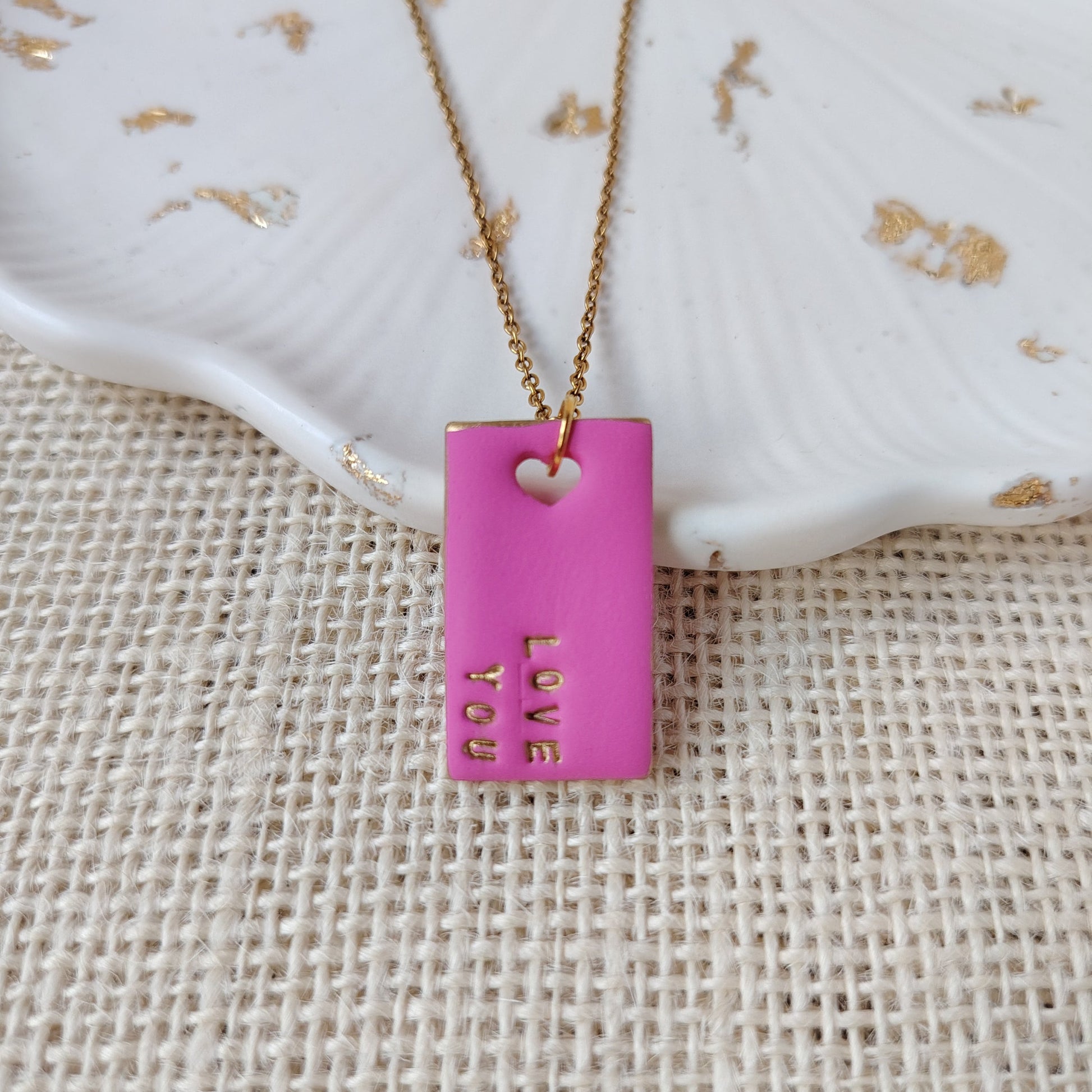 Necklace with a pink pendant on a textured beige surface