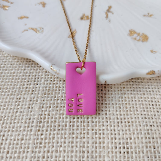 Necklace with a pink pendant on a textured beige surface