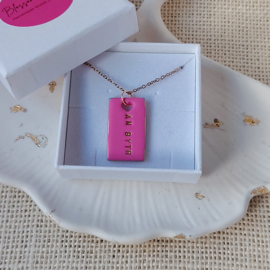 necklace with pink clay pendant in a white box on a textured surface