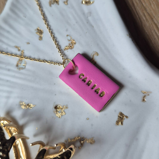 Pink polymer clay rectangle necklace with heart cut-out and the word Cariad, meaning love in Welsh