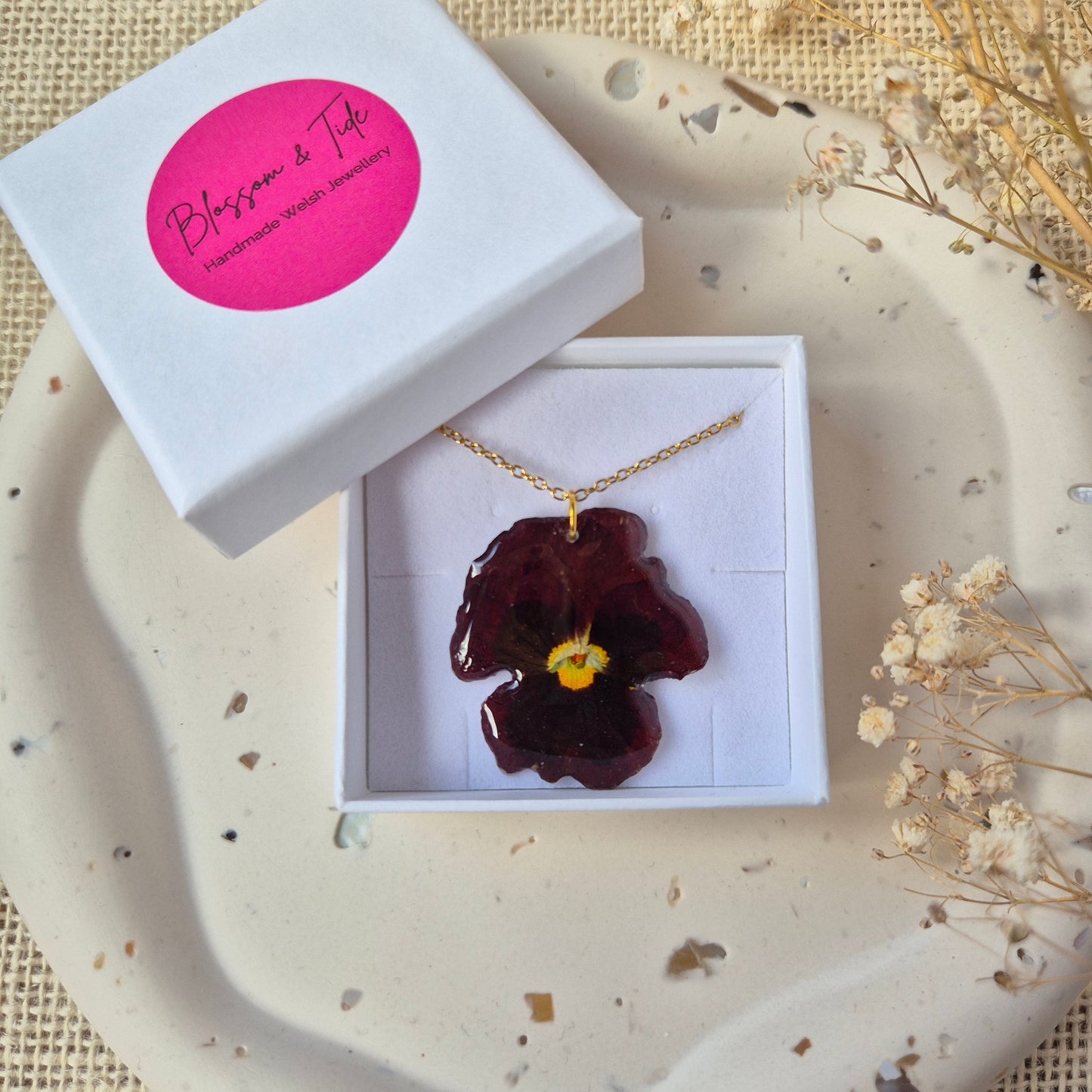 Handmade pressed pansy necklace shown in a branded gift box. 