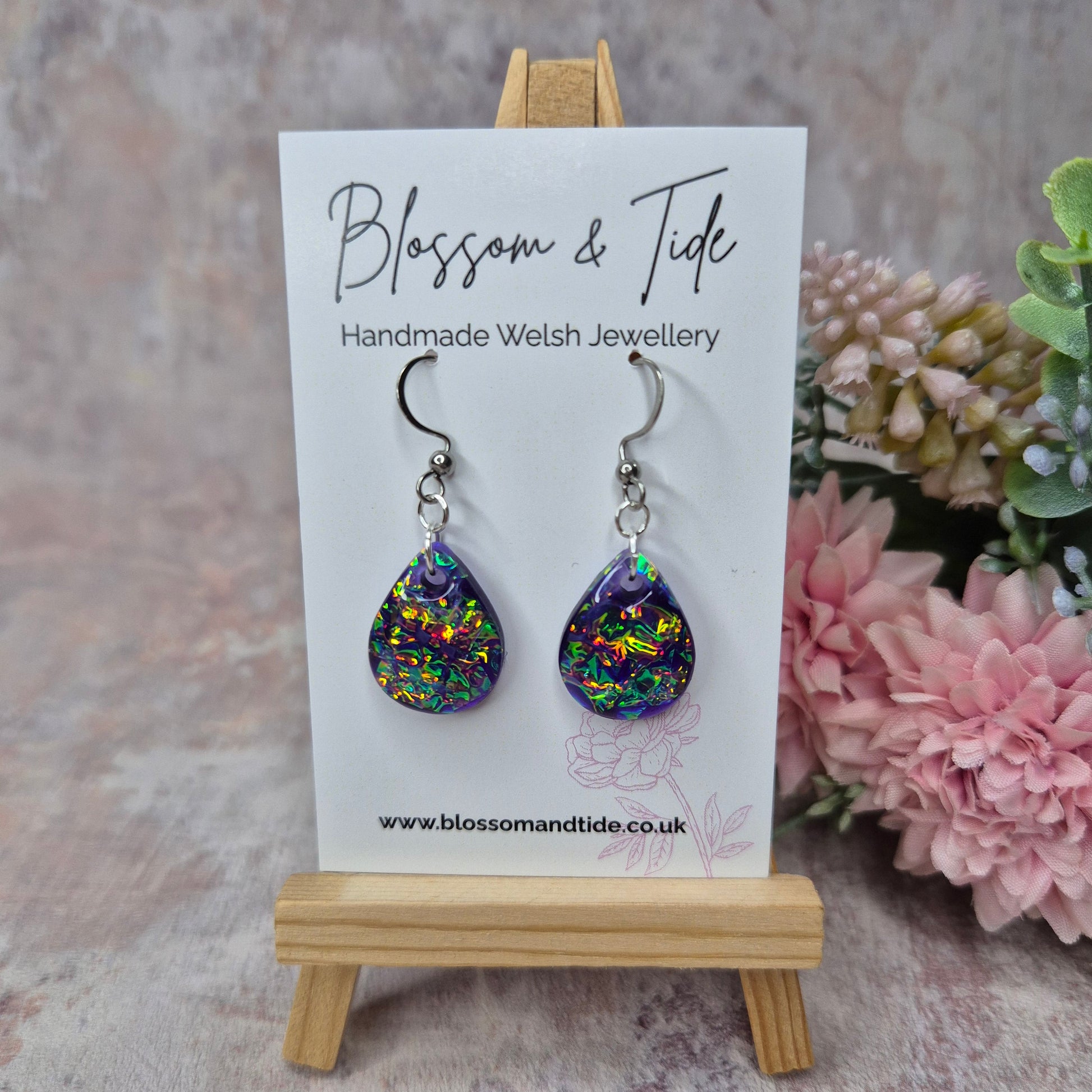 Teardrop purple dichroic resin earrings on a branded Blossom & Tide card , against a pink background