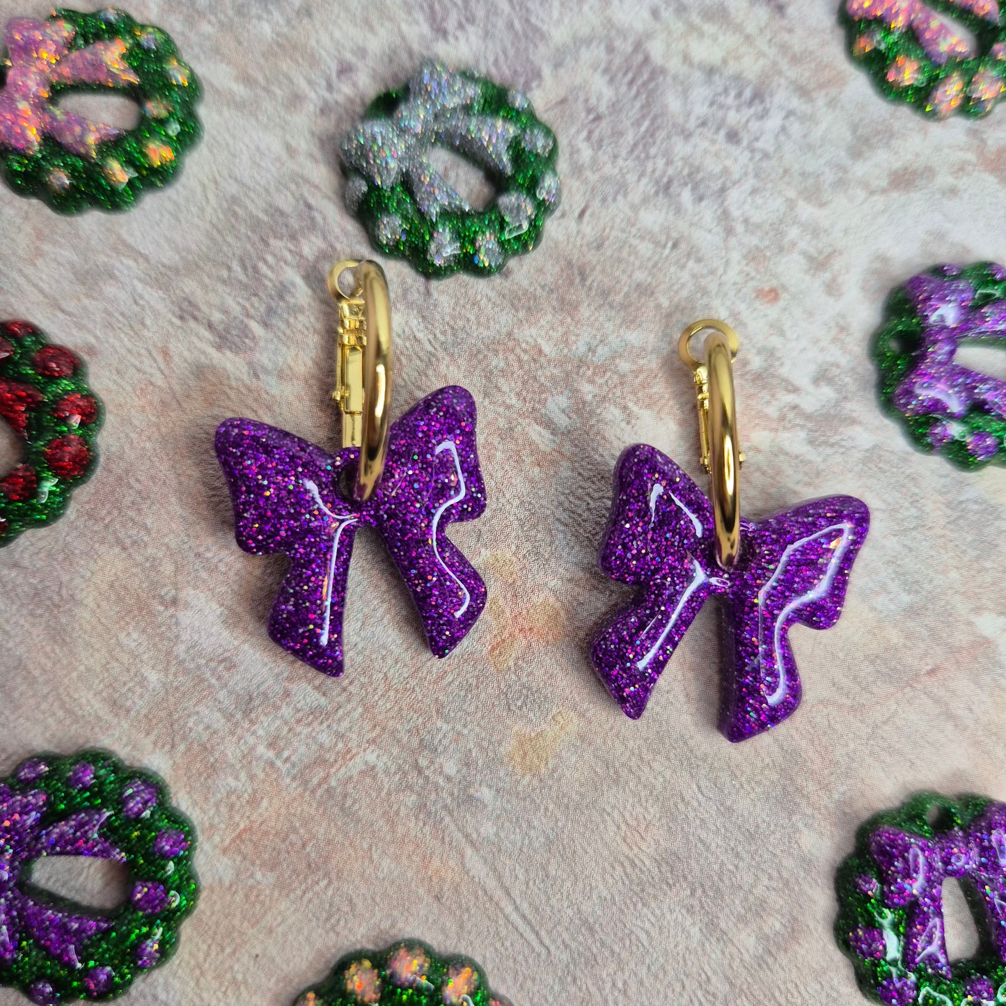 purple glitter  earrings on a textured surface
