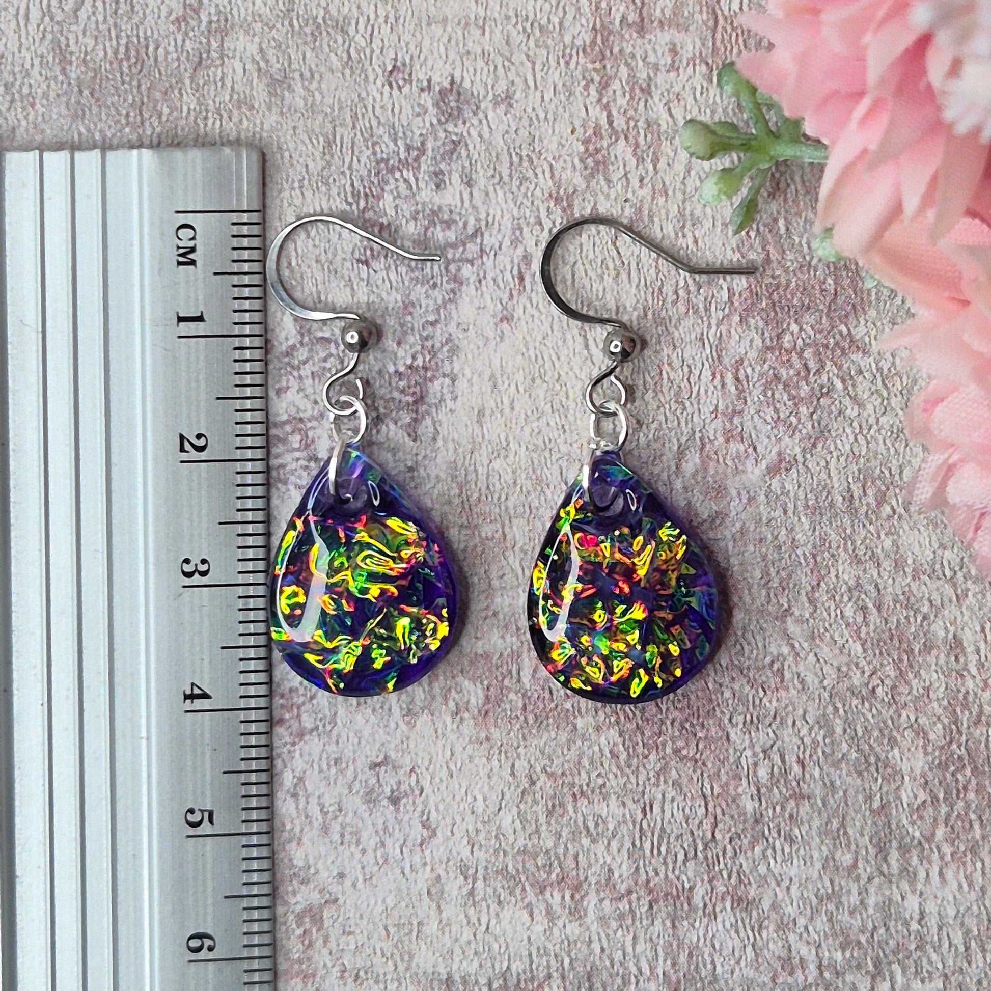 Teardrop shape purple dichroic resin earrings with a ruler as scale reference 