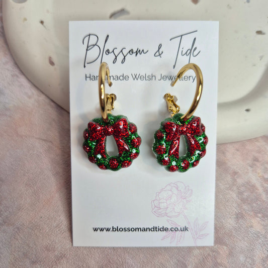 Red and green wreath earrings on a 'Blossom & Tide' card.
