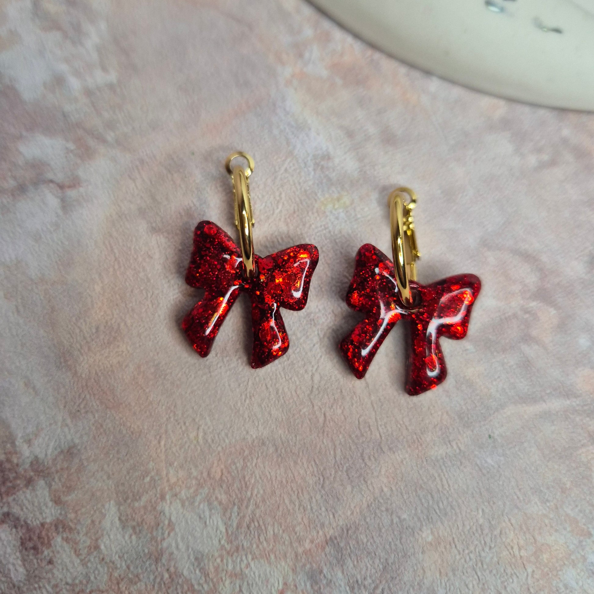  red bow-shaped earrings on a textured surface