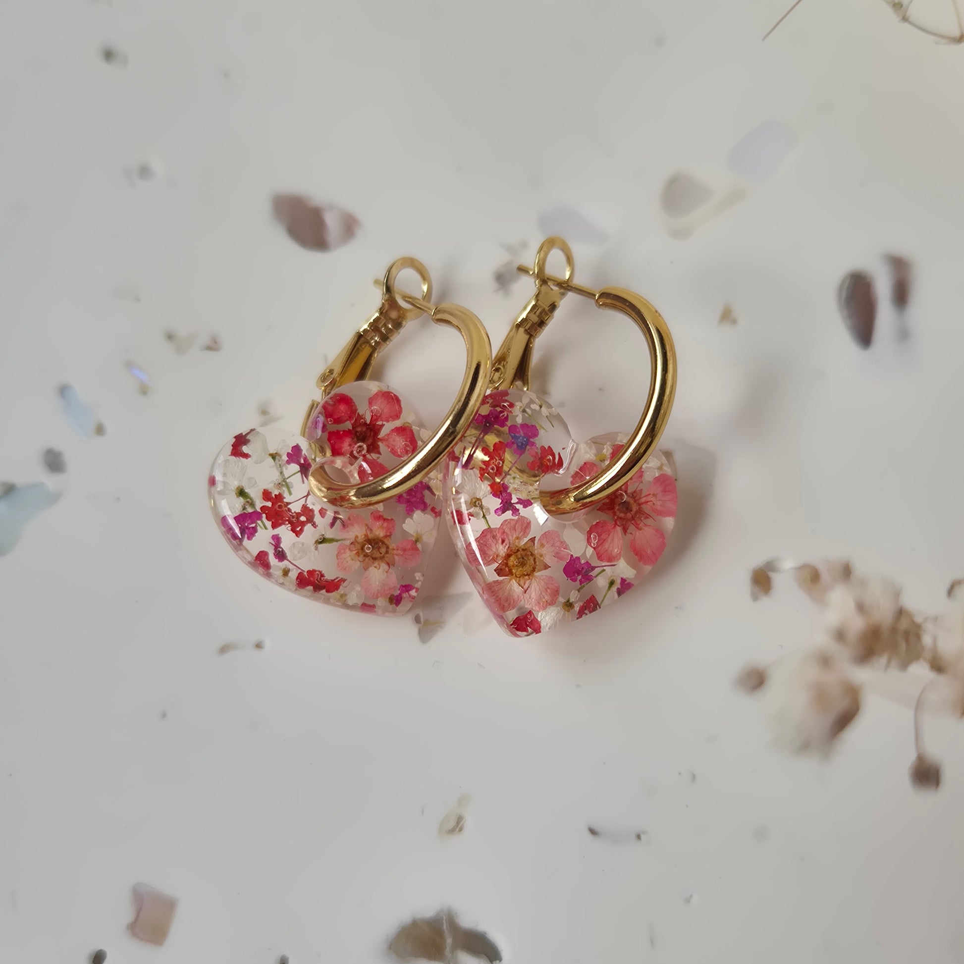 Pair of floral earrings with gold hoops on a light background