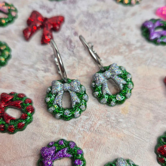 Colorful wreath-shaped earrings on a textured surface
