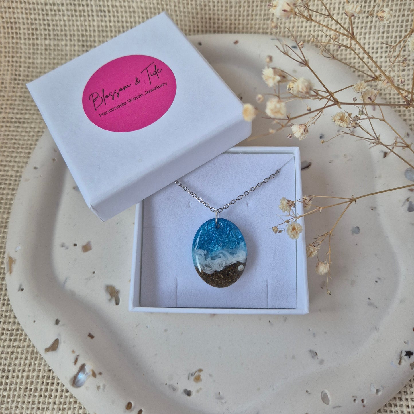 Welsh beach necklace in a box on a textured surface