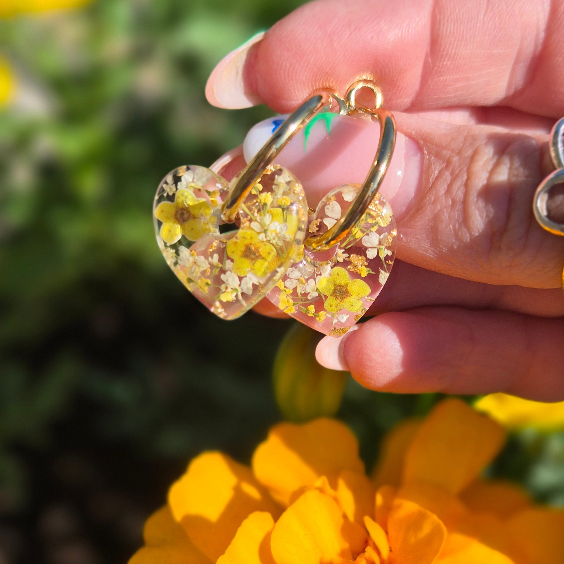 heart shaped resin earrings with real flowers and wood pulp flowers on gold hoops